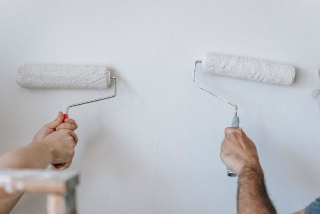 two hands painting a wall